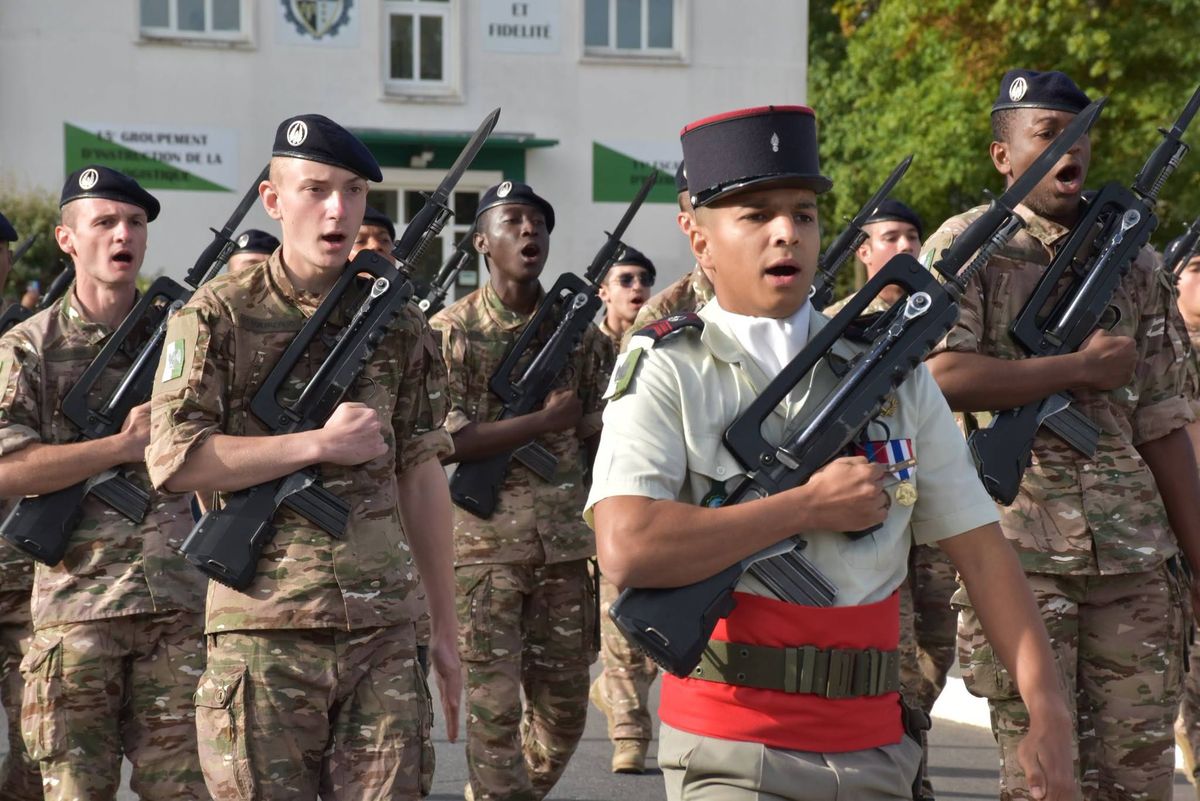 Soldats du régiment au défilé, en tenue de sortie à képi et en treillis à béret