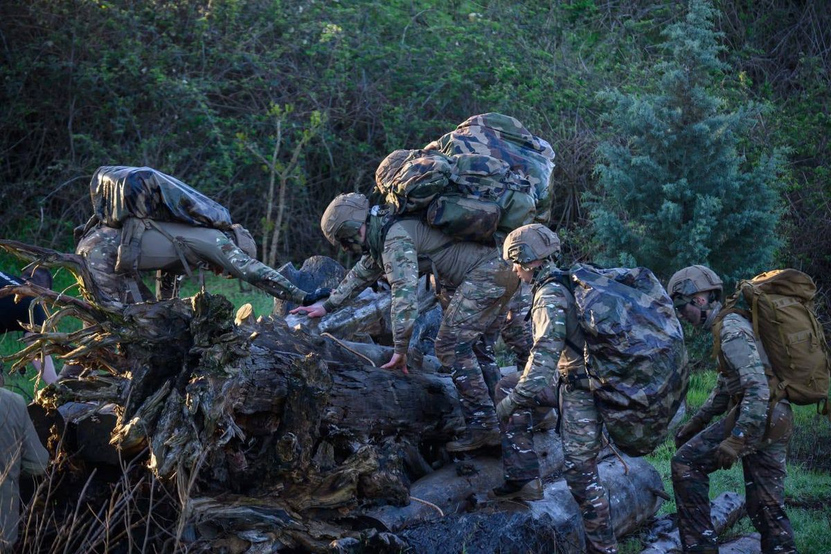 Des soldats franchissent un obstacle, sac au dos