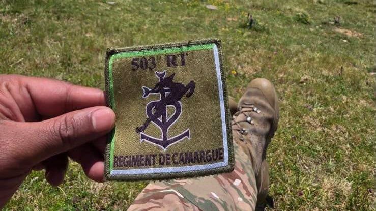 L'insigne d'épaule du régiment, en tissu, tenu à la main en montagne
